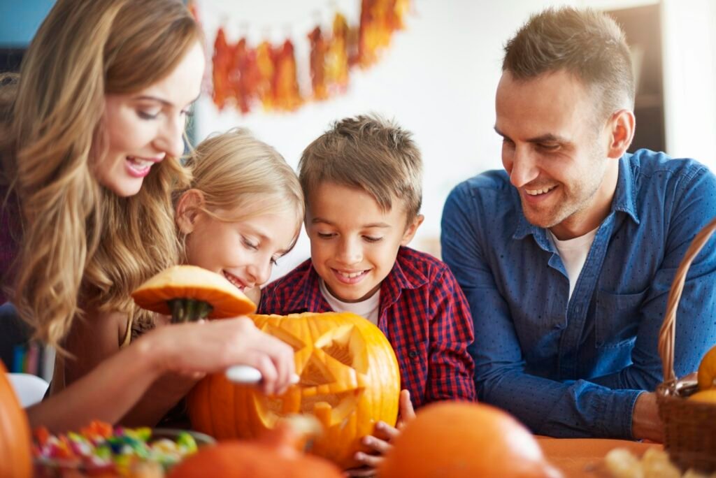 Parents helping children in carving pumpkins